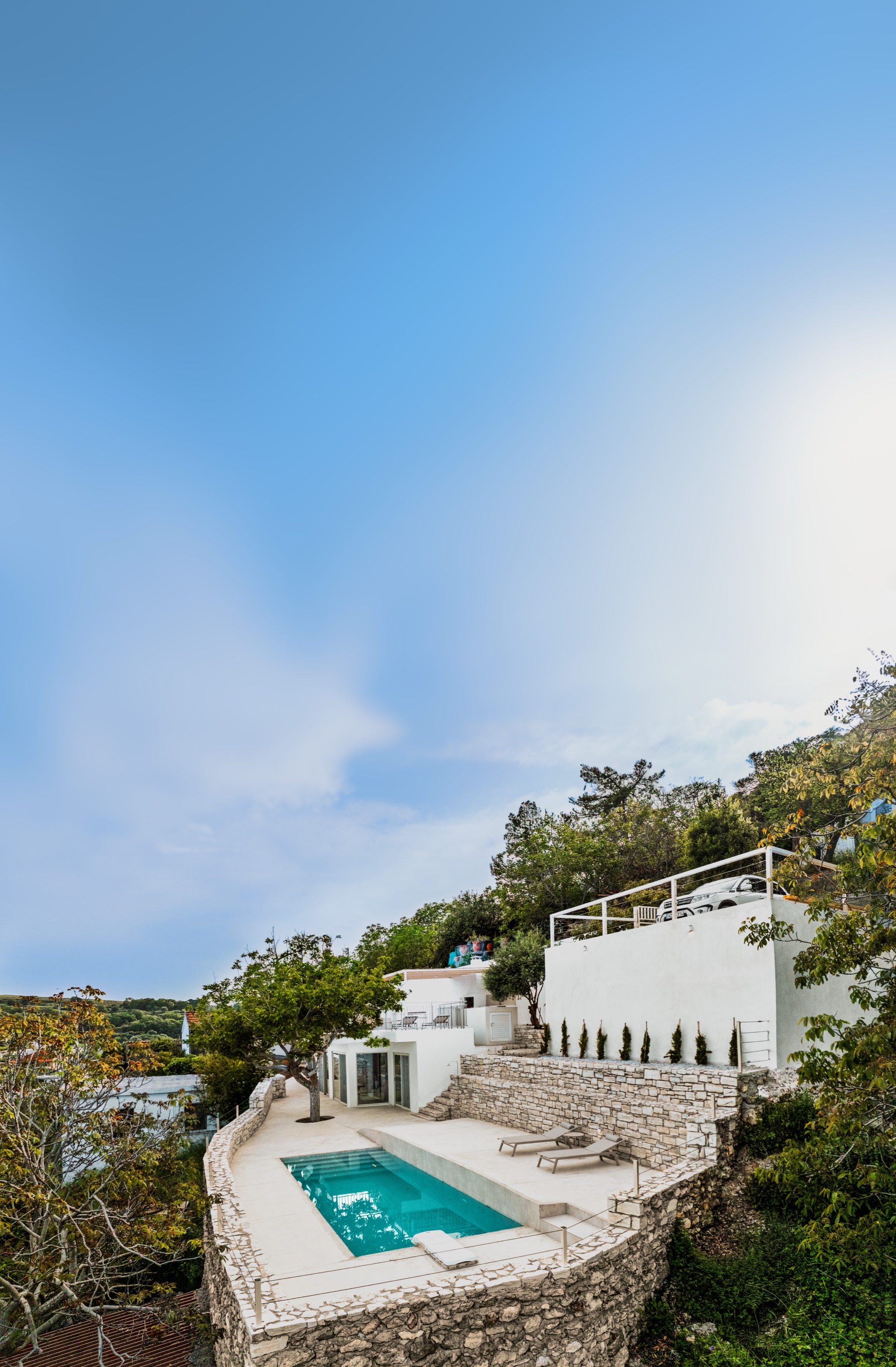 Tall view of Nogal Retreat with the pool, terrace, and white walls beneath a broad blue sky