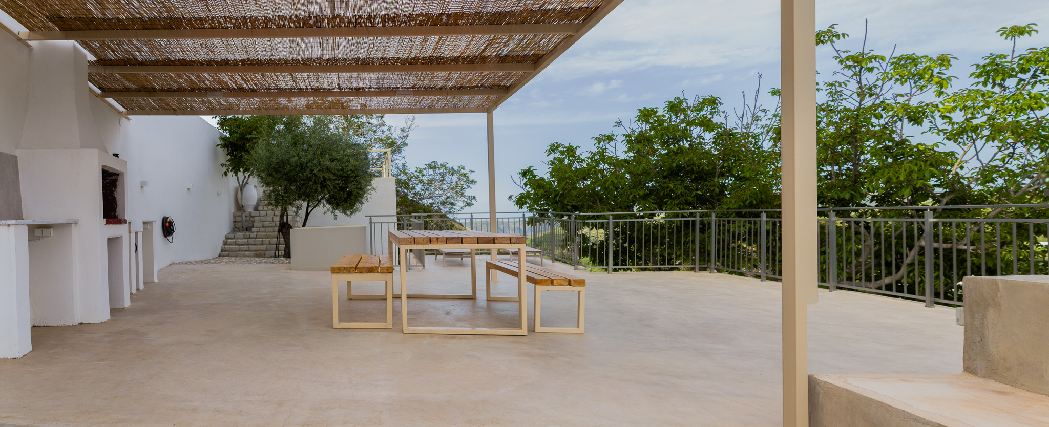 Covered terrace with dining table and open valley view